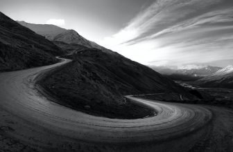 Una strada di montagna in ripida salita in bianco e nero.