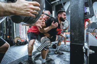 Atleta mentra esegue un back squat per il suo programma di forza.